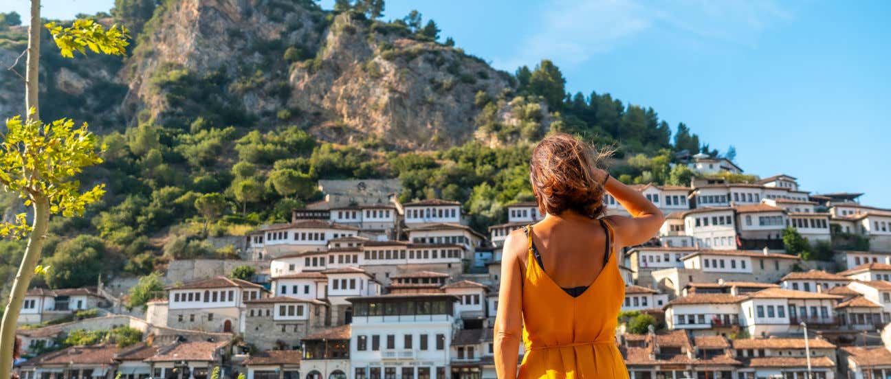 Una donna di spalle guarda un gruppo di case bianche sul fianco di una montagna