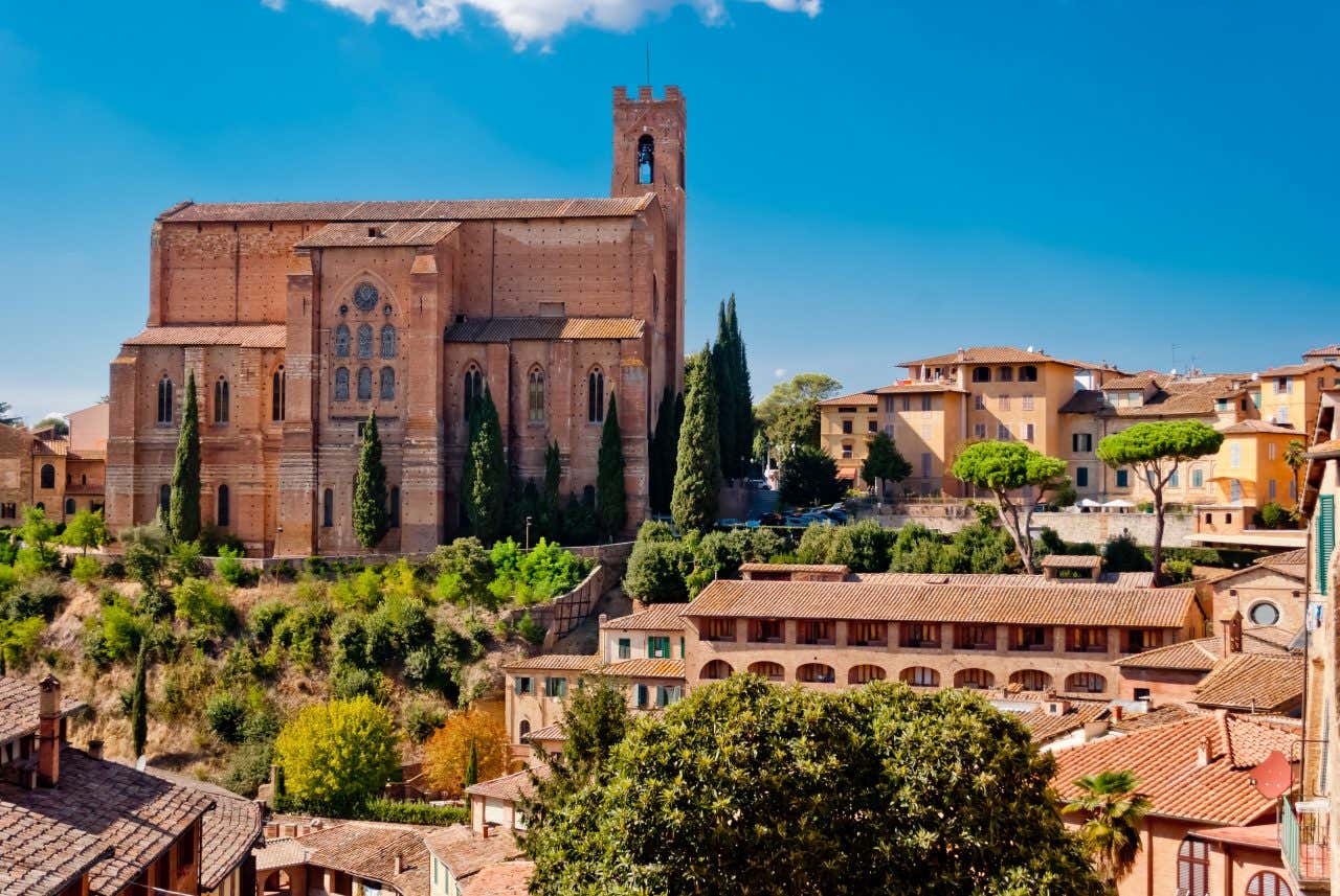 Una basilica medievale in mattoni arancioni e dai soffitti altissimi, poggiata in cima a un piccolo colle, sovrasta le case del centro storico con cui confina