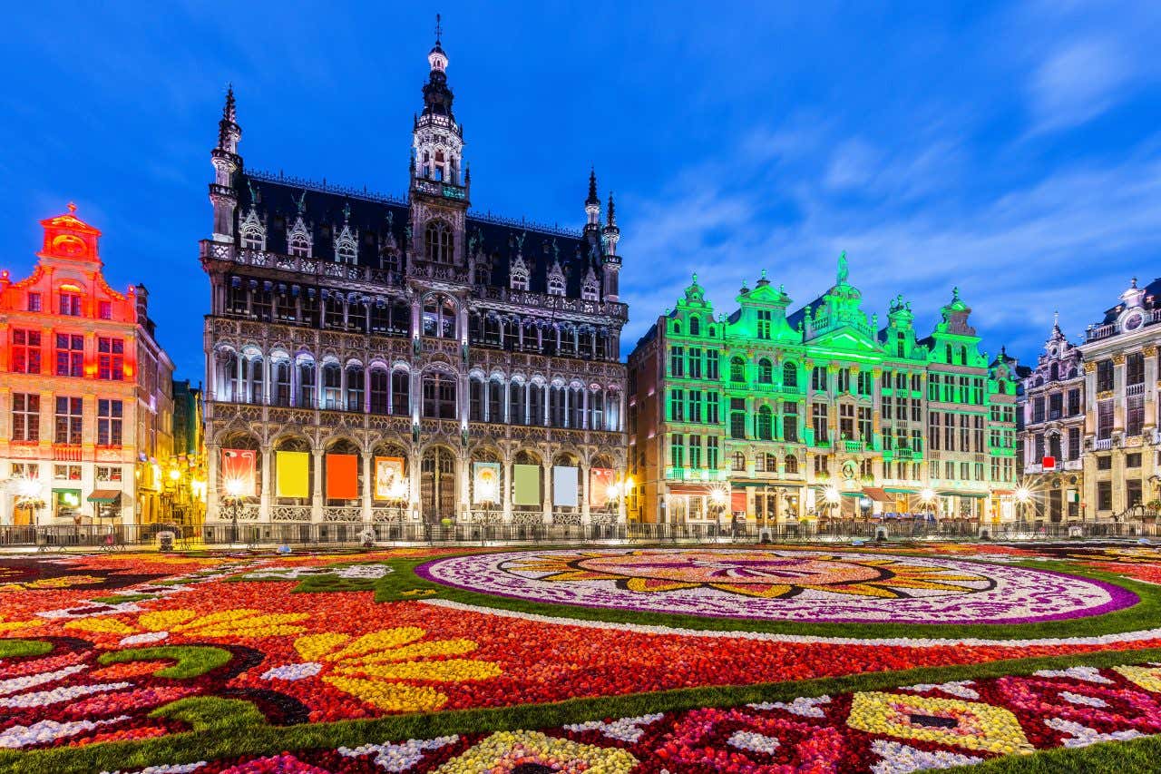 Grand-Place recouverte d'un parterre de fleurs à la tombée de la nuit et bâtiment illuminés