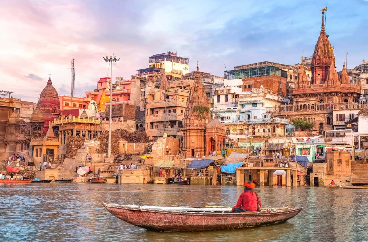 Vue sur Varanasi et le Gange, avec une petite barque et un homme dedans au premier plan