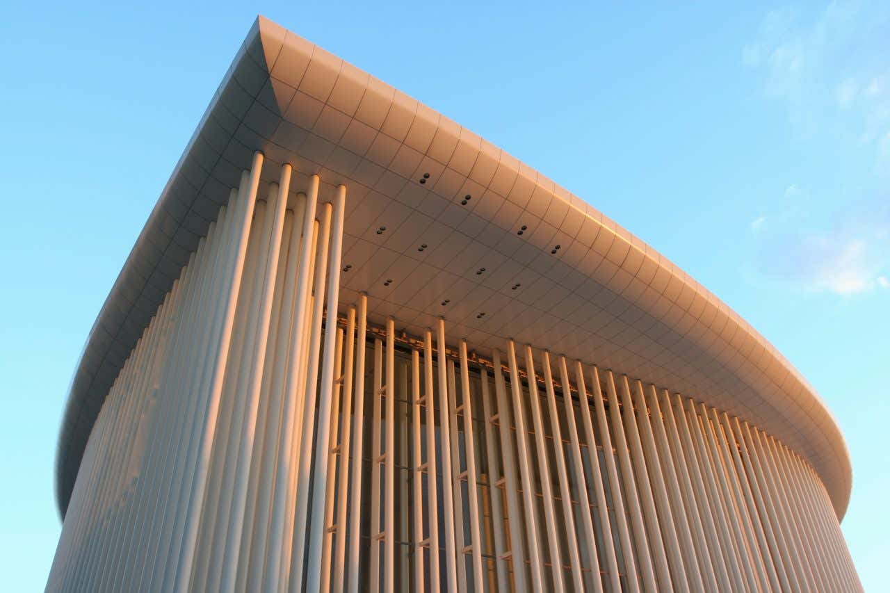 A white building with many vertical columns at sunset