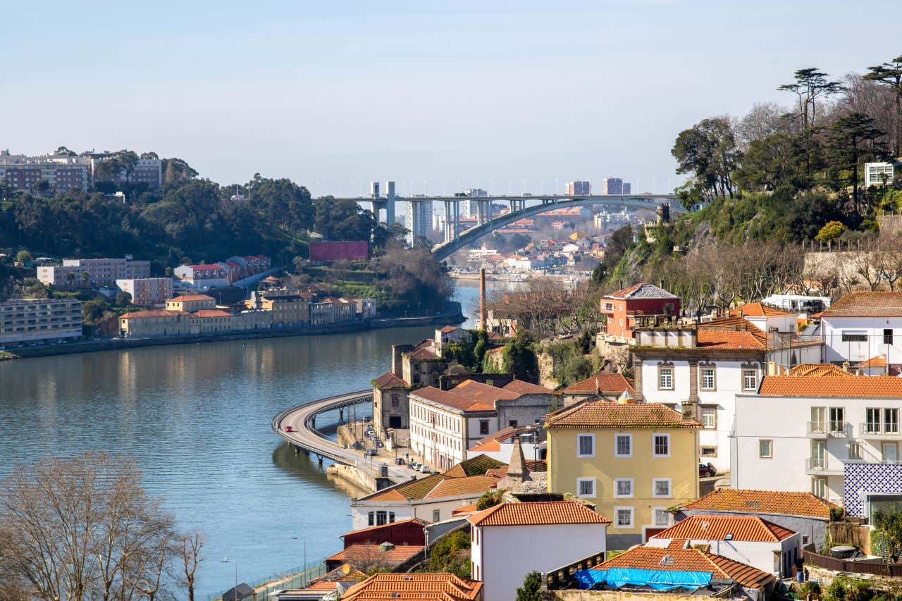 Scenic view of Porto with buildings, the Duoro River, and one of the six bridges in the distance on a sunny day