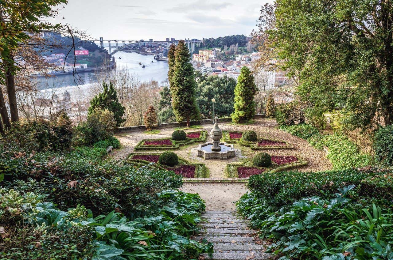 A garden with vegetation and a fountain with views of the Duoro River, the city of Porto, and a bridge