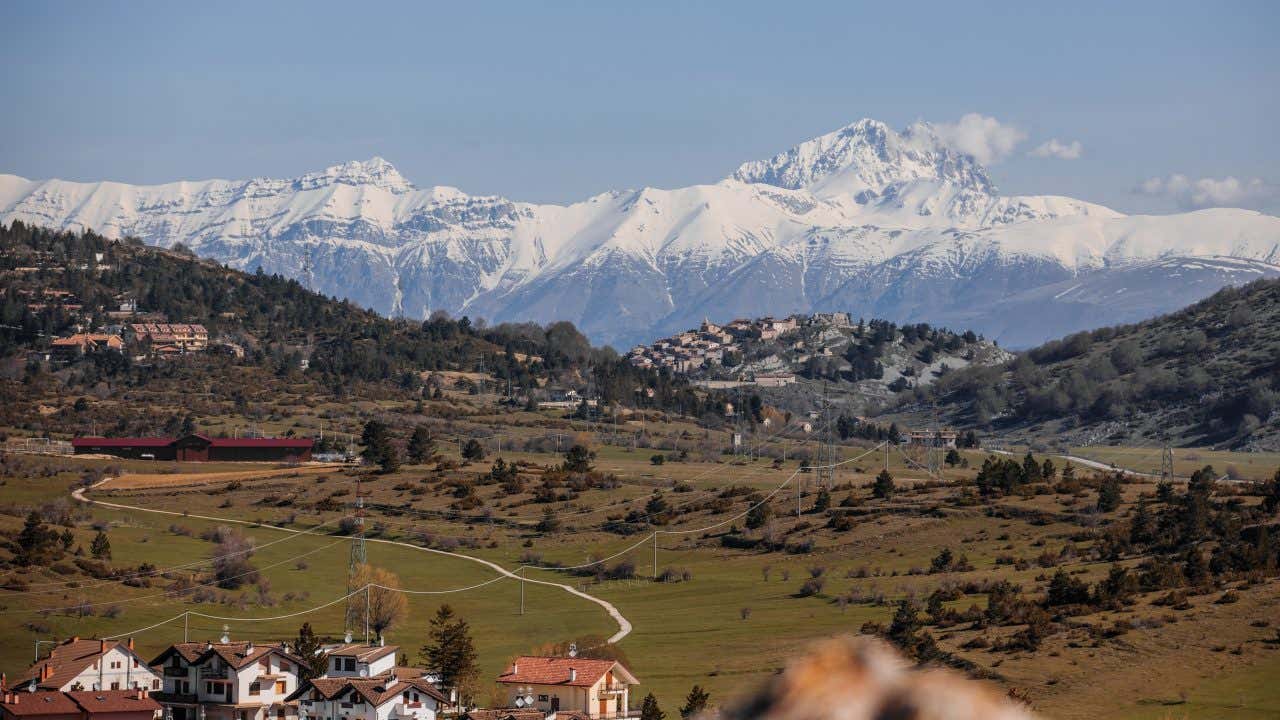 Una montagna innevata in lontananza nei pressi di un piccolo borgo in pietra in Abruzzo