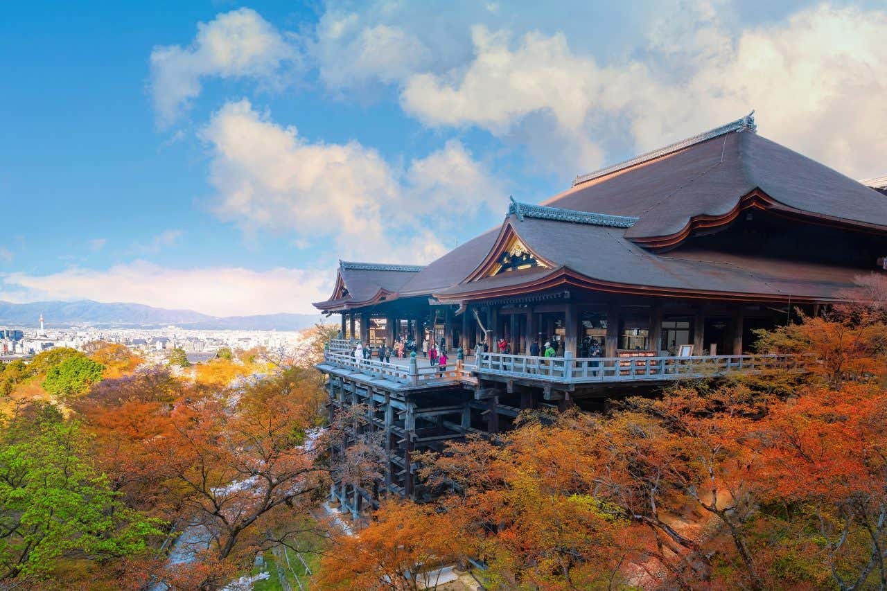 Kiyomizu-Dera's wooden stage during the autumn, with a cloudy blue sky in the background.