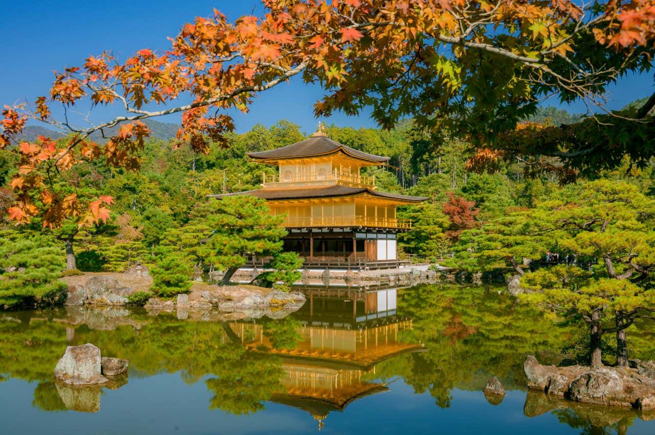 The Golden Temple in Kyoto seen over water with a clear blue sky in the background.