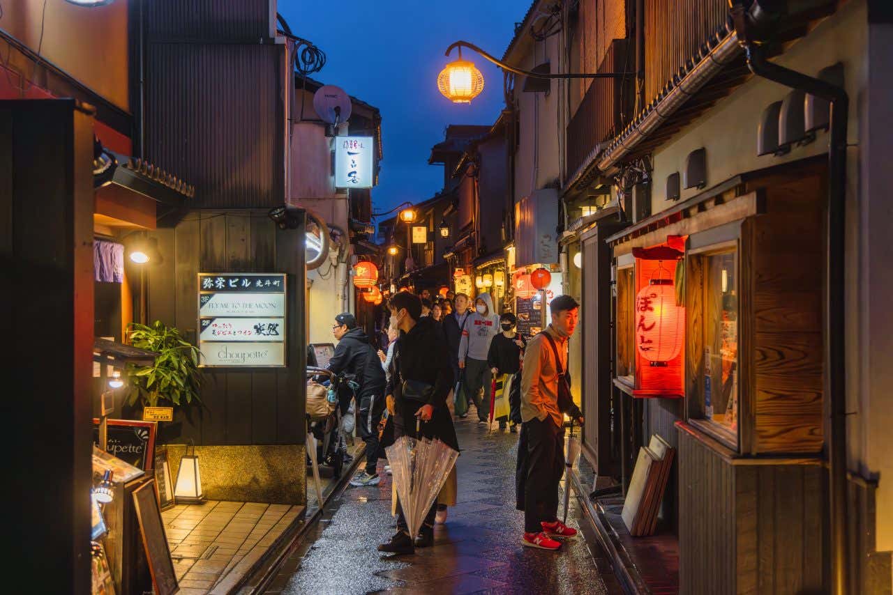 The Pontocho District at night, with lanterns lit along the path and people walking up and down.