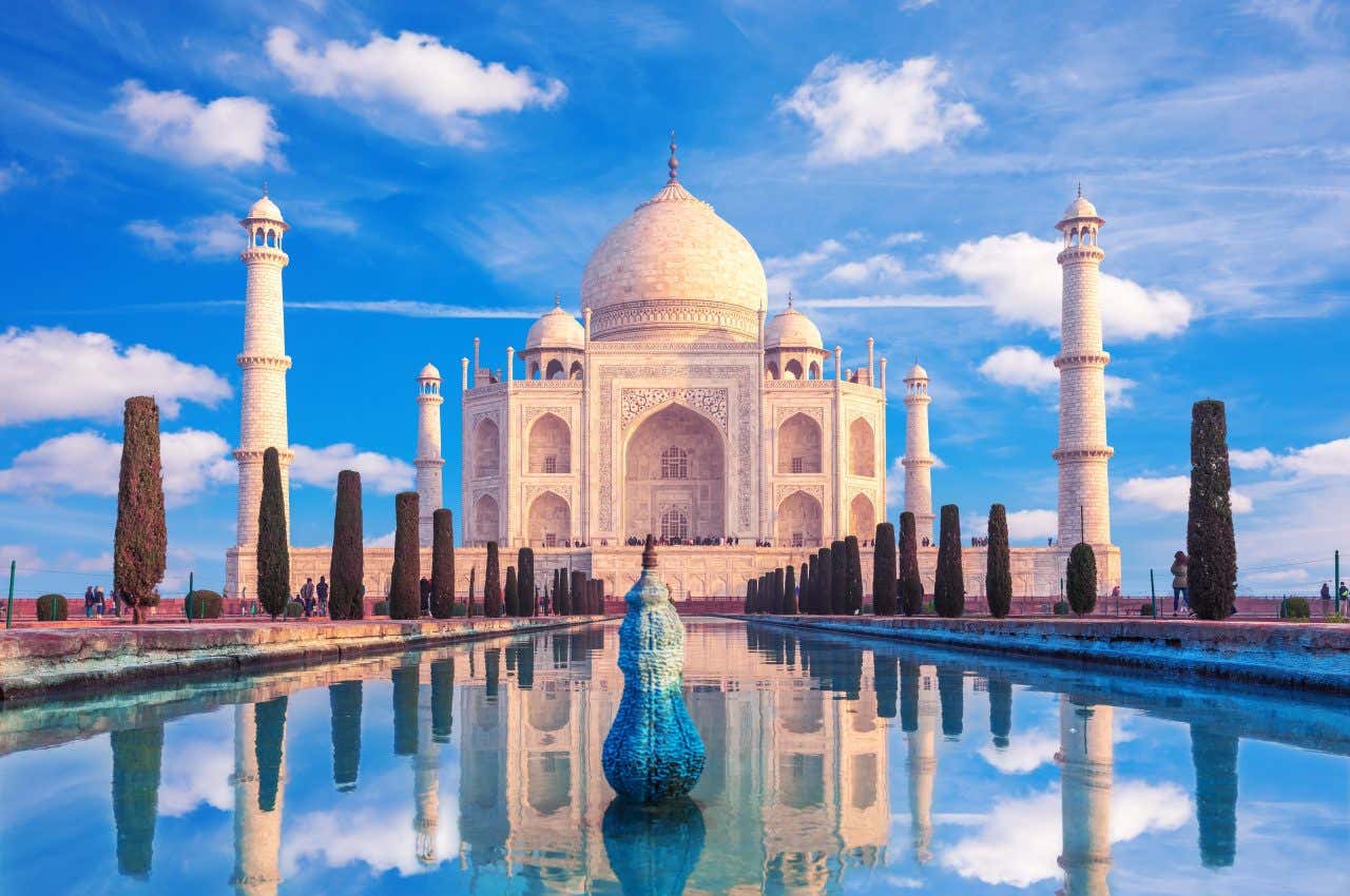 O imponente Taj Mahal no centro com um céu azul ao fundo