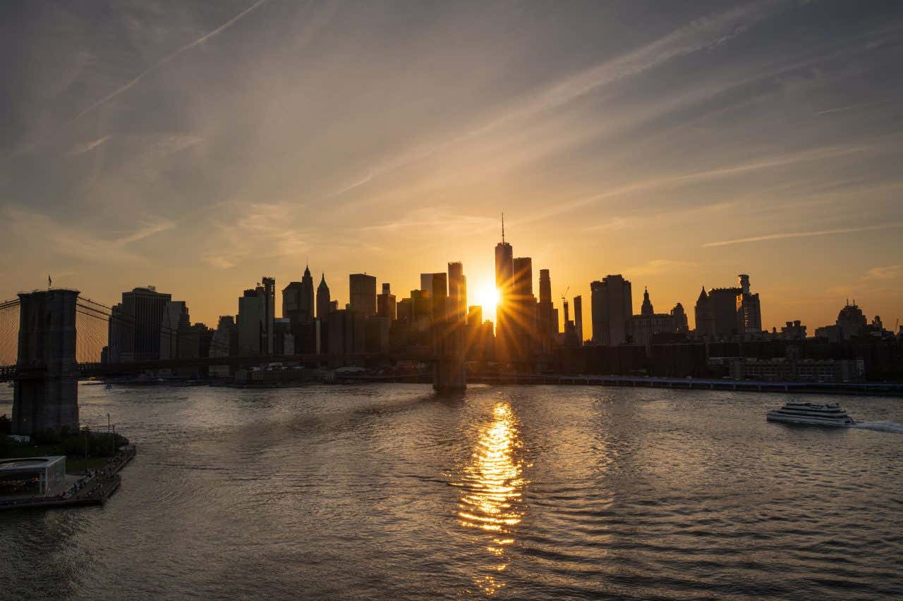 The sun setting behind the skyline as seen from the Hudson River.