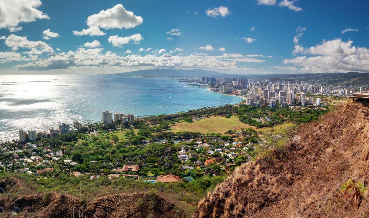 An aerial view of Hawaii as seen from afar, with a blue cloudy sky in the background.