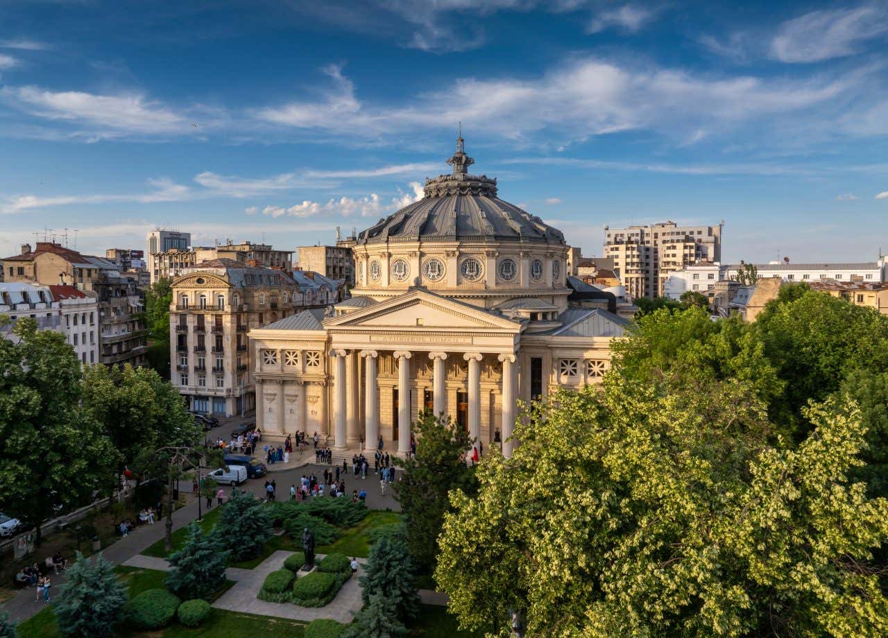 Un grande palazzo a forma di tempio, sormontato da una cupola circolare in stile neoclassico davanti a un giardino e circondato da altri palazzi più bassi