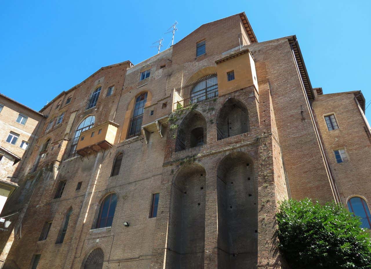 Facciata esterna di un palazzo medievale del centro di Siena in una giornata di sole