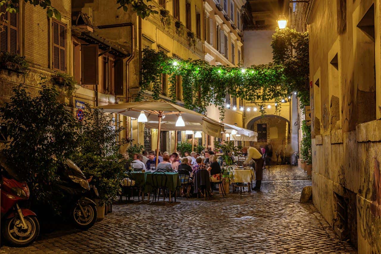 Terrasse d'un restaurant éclairé la nuit dans une rue de Trastevere, un quartier que nous vous recommandons si vous vous demandez que faire à Rome le soir