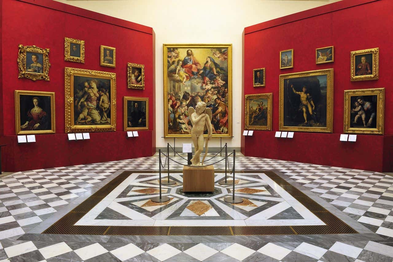 Uma das salas da Galeria Uffizi repleta de obras de arte do período Renascentista e uma escultura ao centro