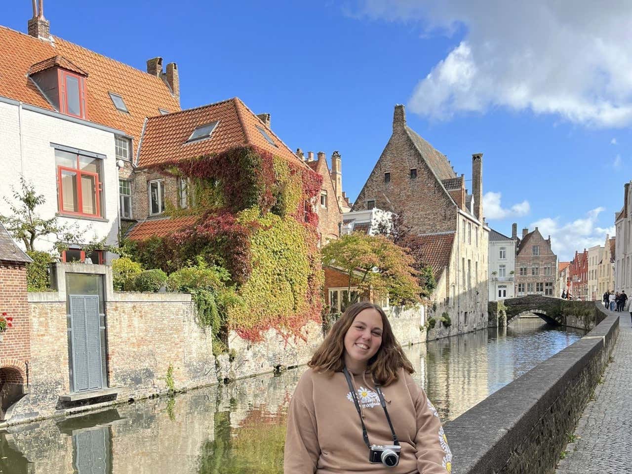 Clara Aragón posando para una foto con los canales de Brujas de fondo en un día soleado