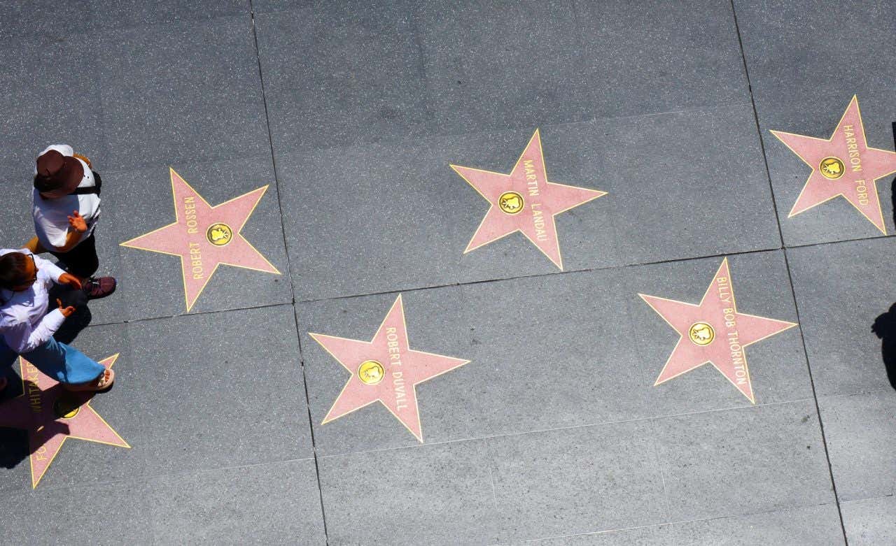 Vista de cima de algumas estrelas da Calçada da Fama de Hollywood com pessoas passeando por elas