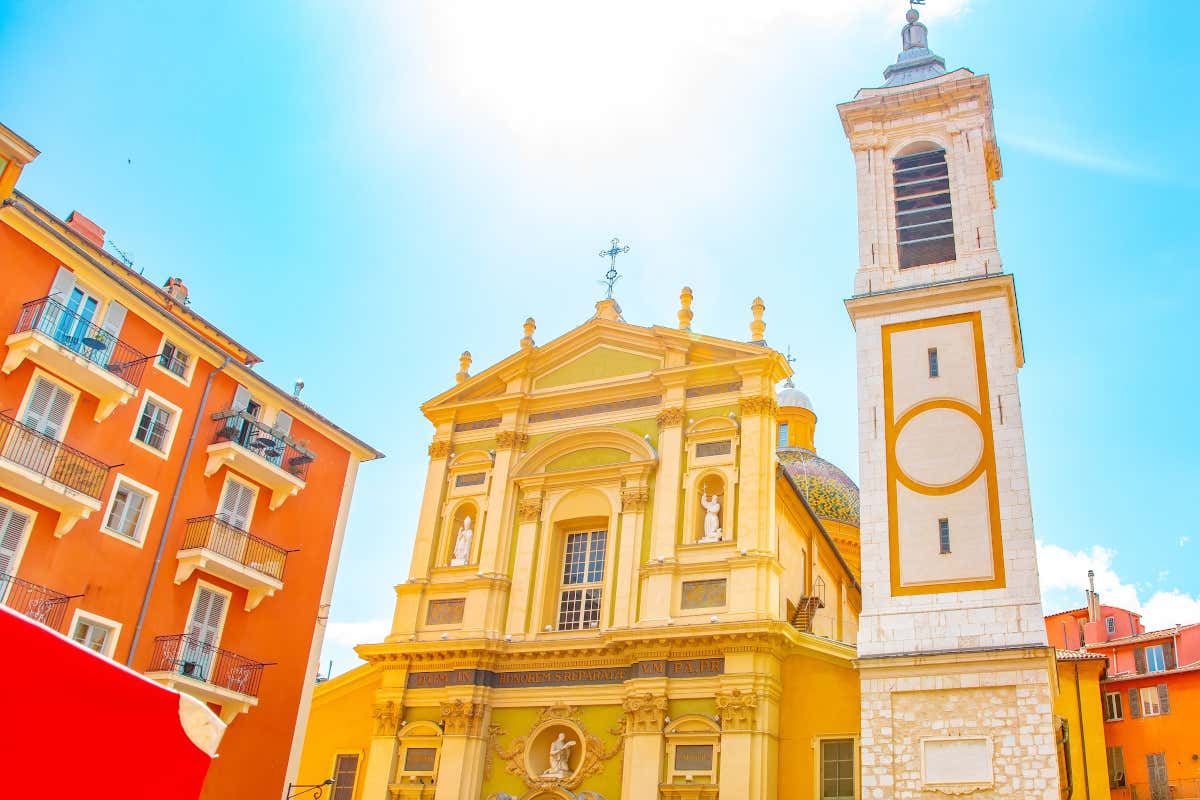 Fachada de una catedral de color amarillo con un campanario blanco en una plaza del Vieux-Nice, el barrio del centro histórico de Niza