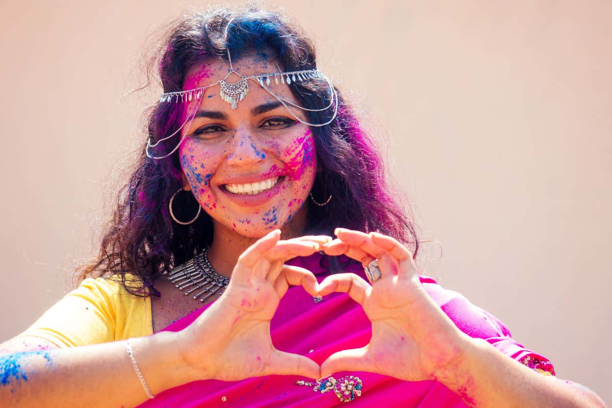 Una mujer hindú con polvos de colores por sus manos y brazos tras celebrar el festival Holi en la India