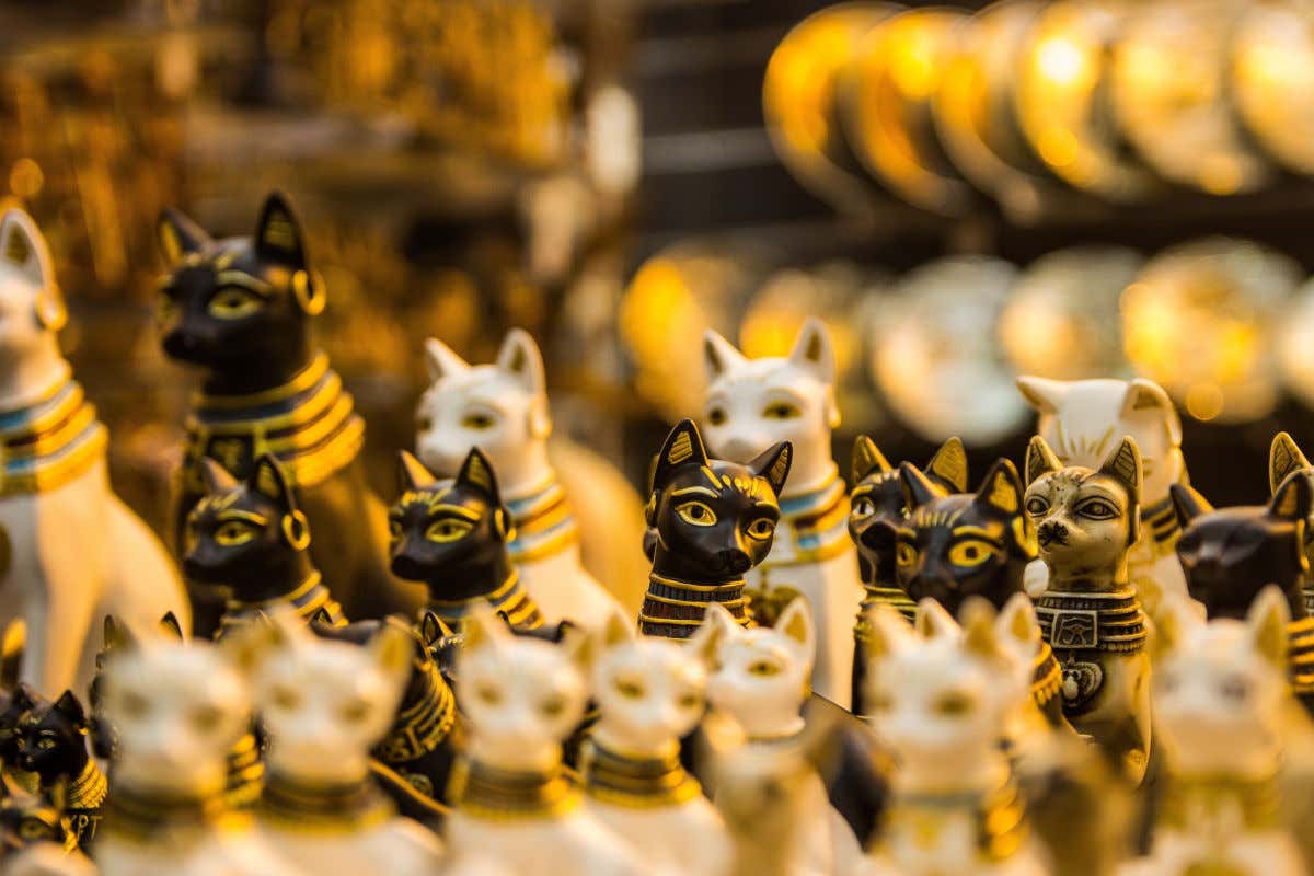 Numerous small cat figurines on display in an Egyptian bazaar.