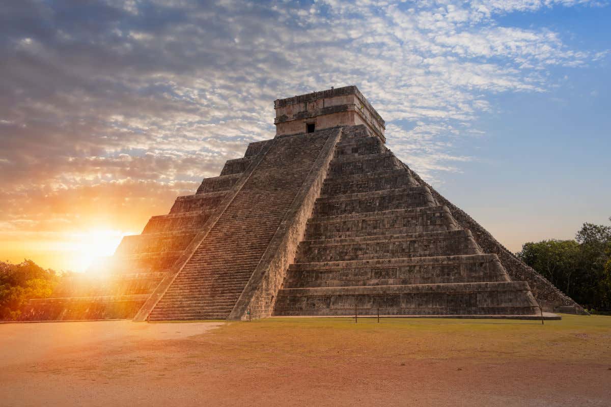 Una de las pirámides de Chichén Itzá con unas impresionantes escaleras en primer plano y el atardecer en el horizonte