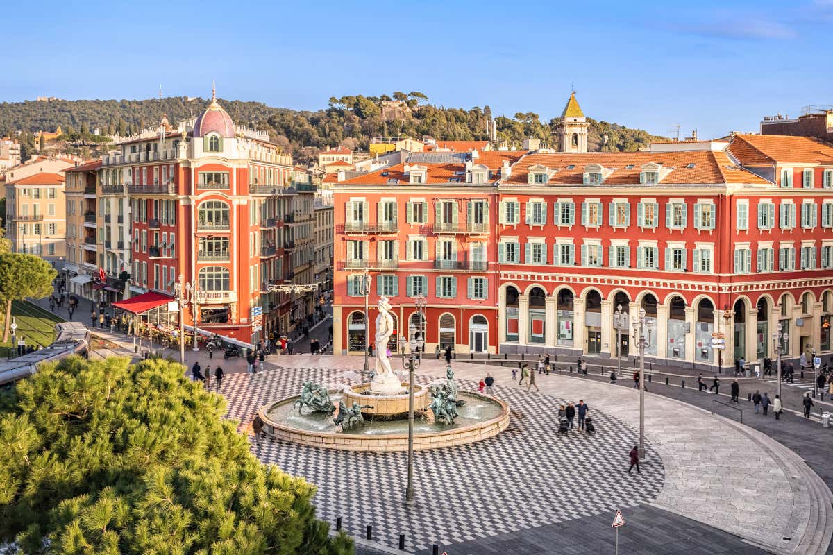 Vista de la Place Masséna, una plaza del centro de Niza donde se ve una fuente en su parte central y unos edificios de color rojo al fondo