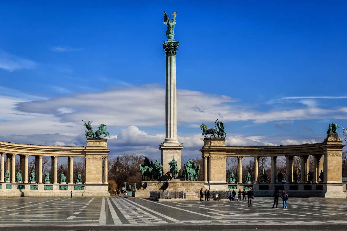 Una enorme columna monumental coronada por un ángel y rodeada de otras tantas esculturas de bronce