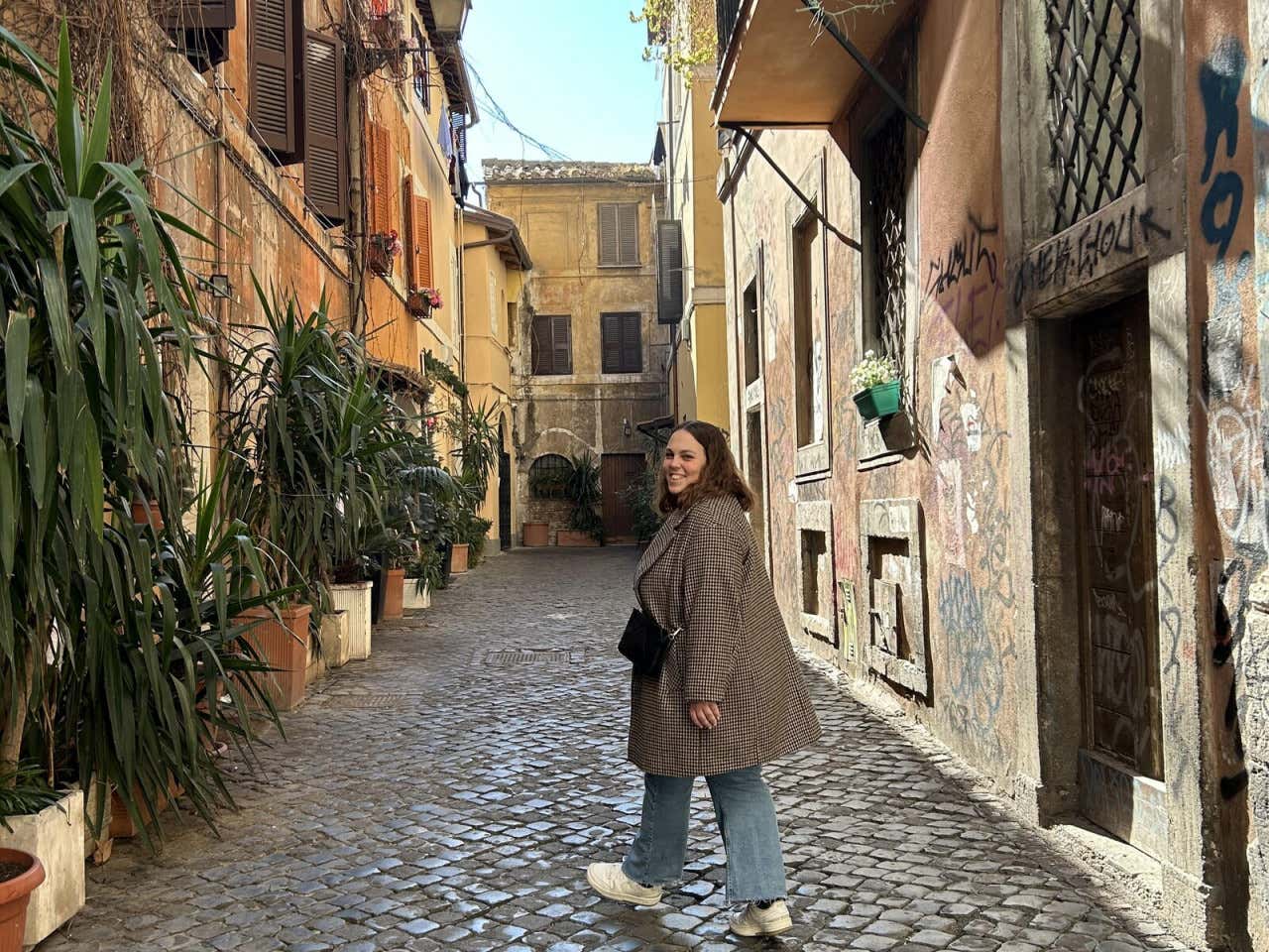 Chica posando para una foto en una calle del Trastevere, en Roma, en un día soleado