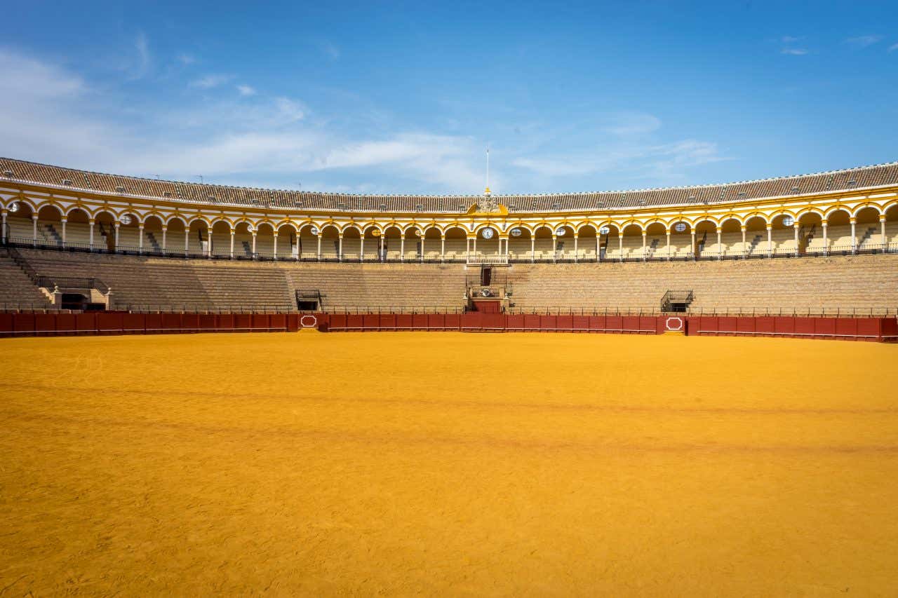 Plaza de Toros de la Real Maestranza with no one inside, and a blue cloudy sky in the background.