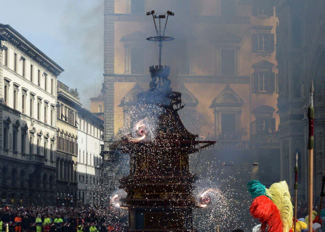 Fuochi d'artificio rotanti montati su un'antica struttura in legno e metallo circondata da una folla di turisti nel centro di Firenze