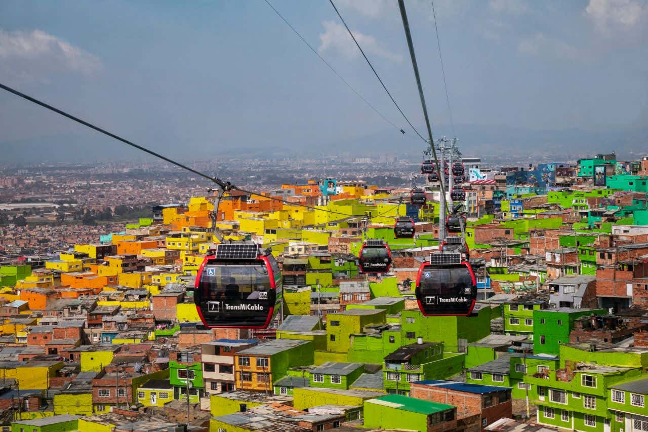 Cable cars in Bogotá, with colorful housing in the background.