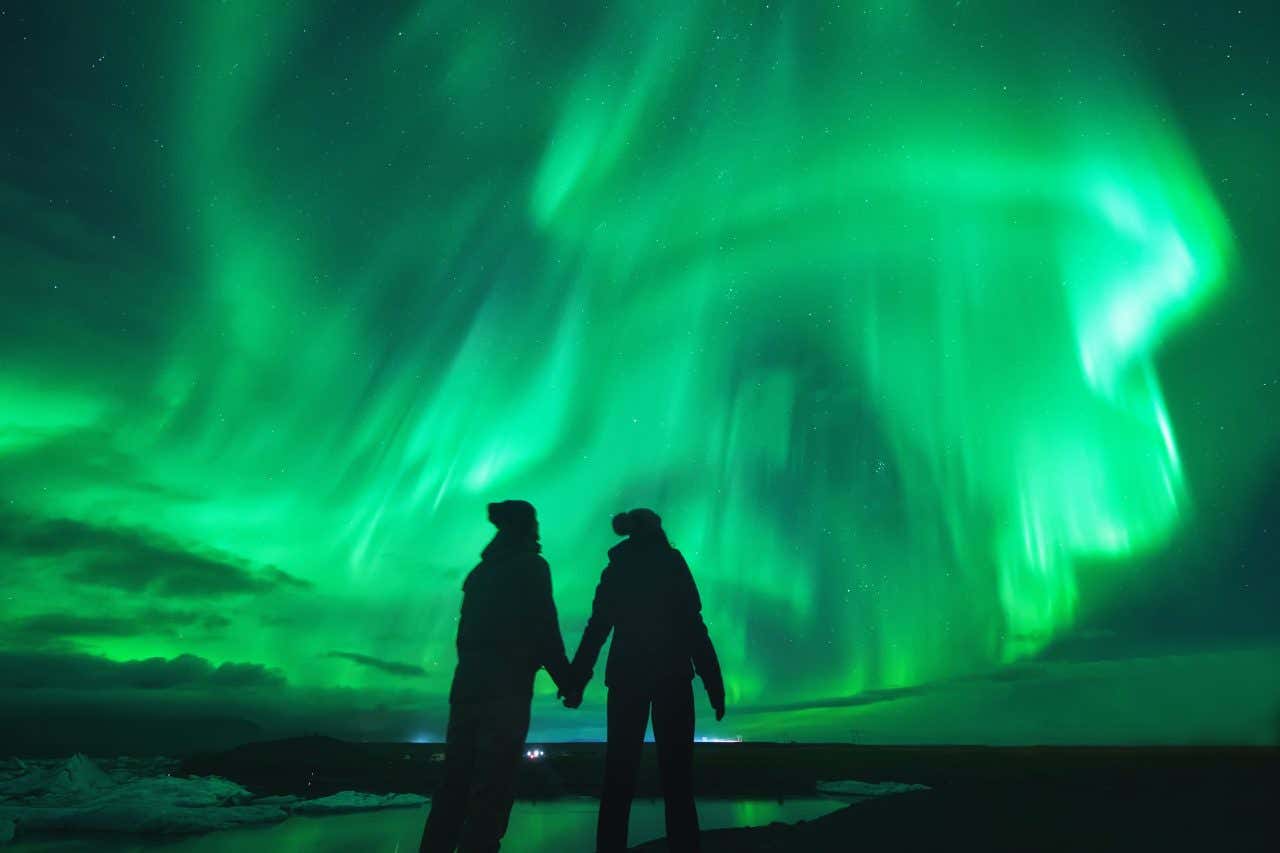 Un couple sous une aurore boréale en Islande, une destination parfaite pour passer une Saint-Valentin 2025 extraordinaire