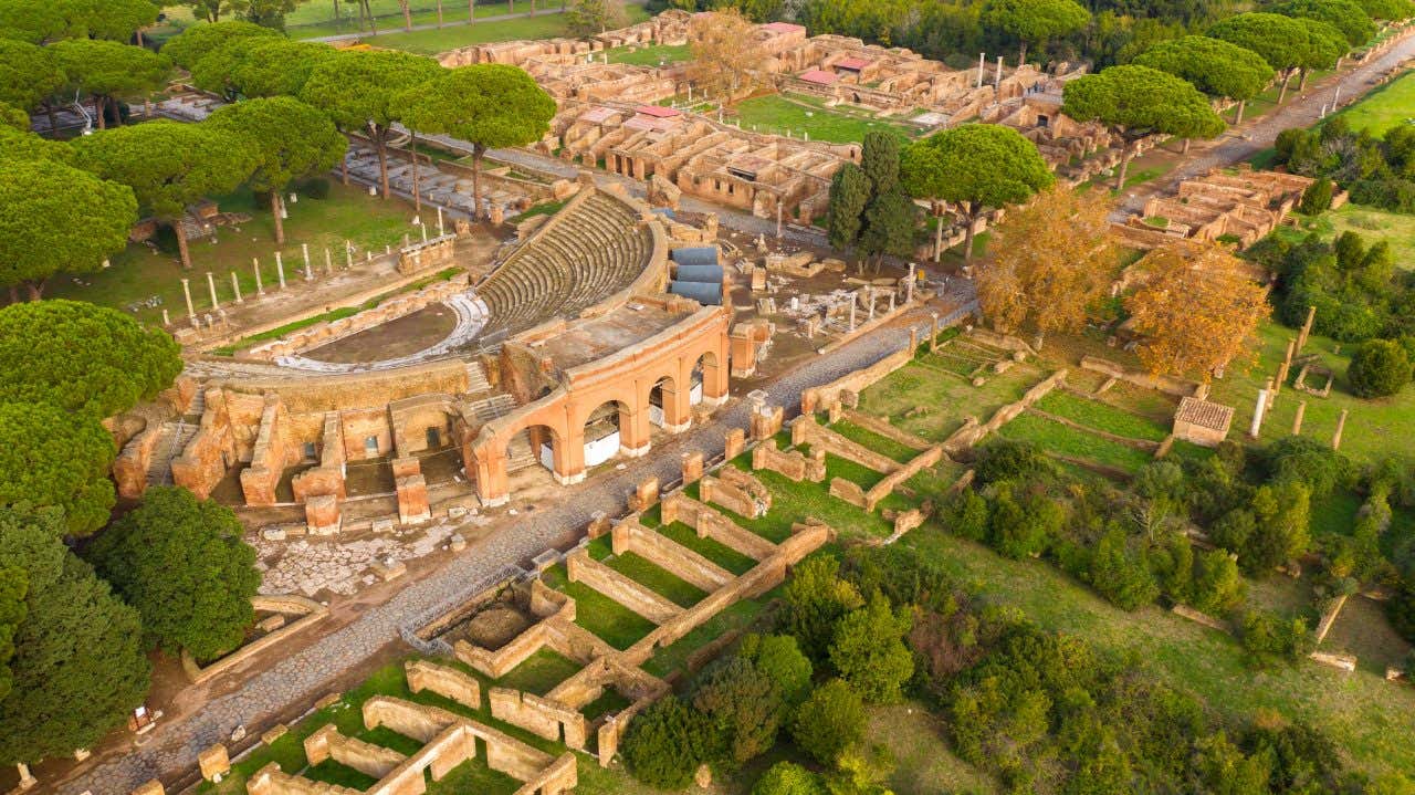 An aerial view of Ostia Antica, with a theater, villas and trees in view.