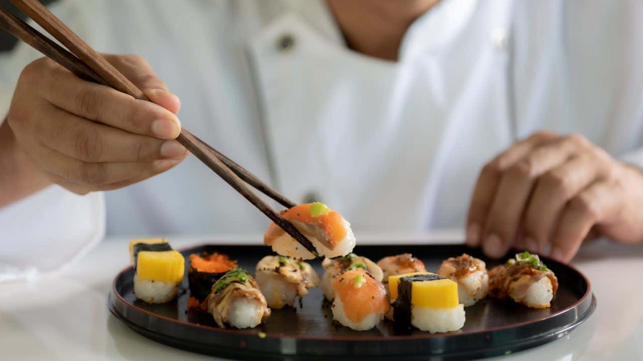 Un chef plaçant des sushis sur une assiette