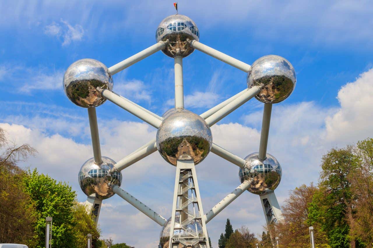 The Atomium, iron crystal magnified 165 billion times, with trees and the sky in the background.