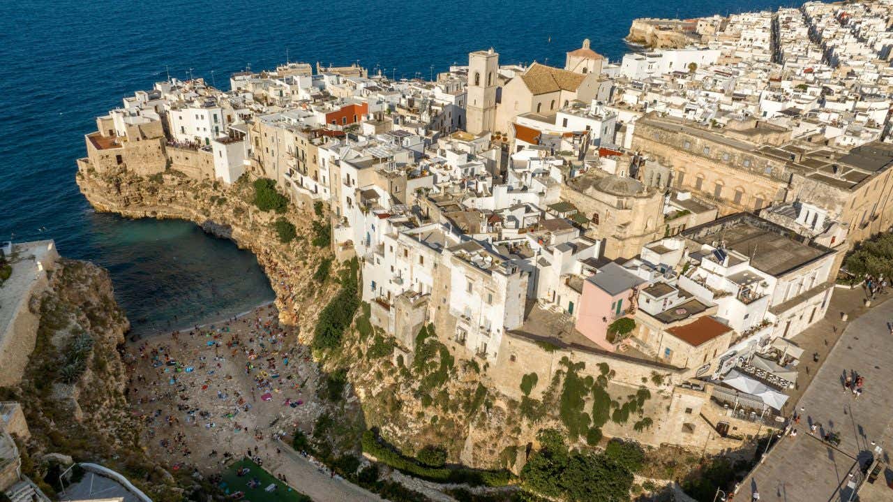 Vista del borgo marittimo di Polignano a Mare, arroccato sugli scogli e in basso a sinistra una piccola spiaggia nascosta tra le rocce