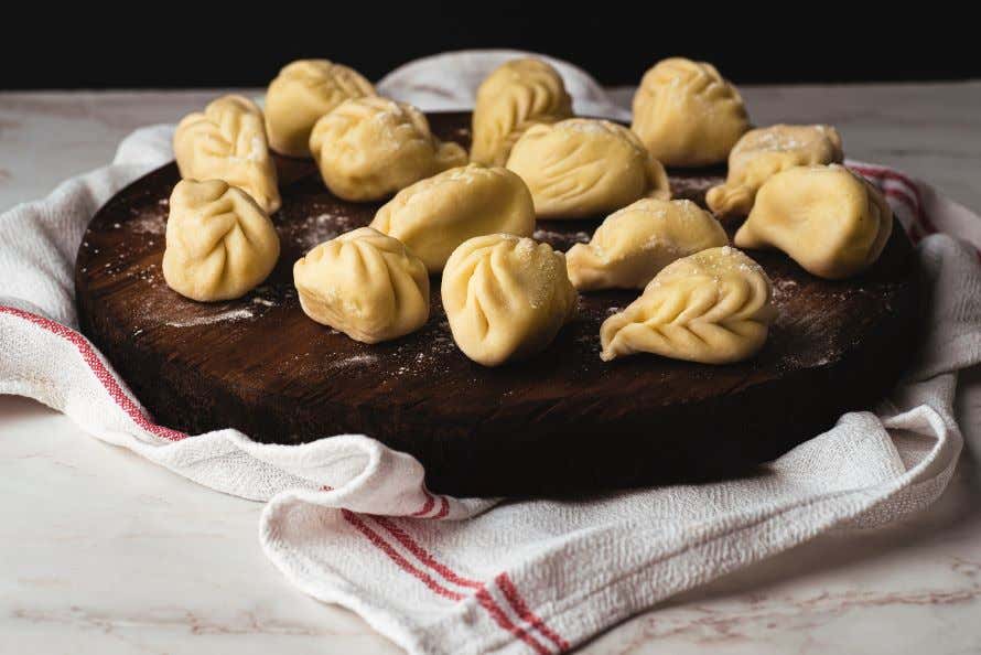 Several Culurgiones on a wooden board, made fresh with flour sprinkled on them.