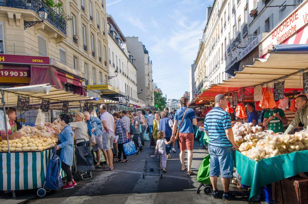 The Marché Bastille in Bastille with lots of customers and vendors in view and a cloudy sky in the background.