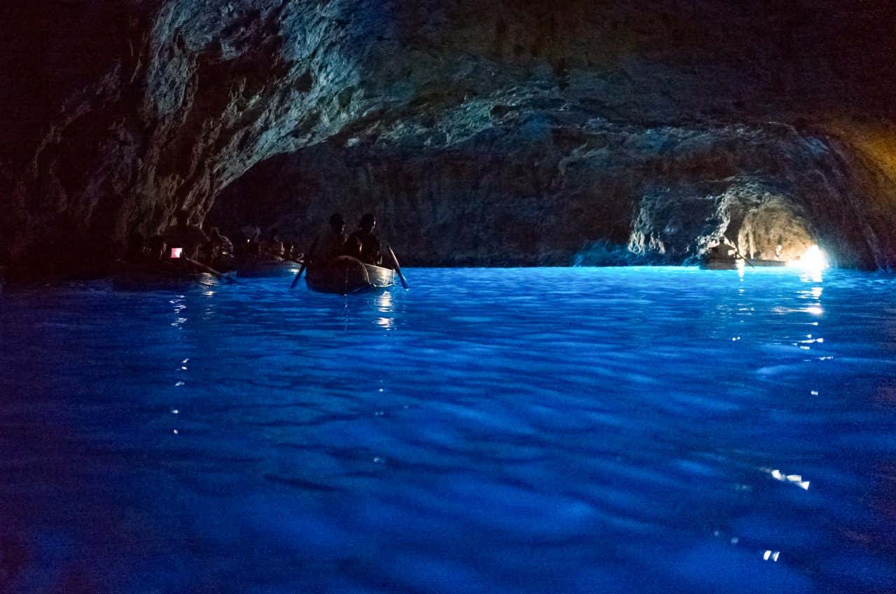 An underwater shot of the Blue Grotto in Capri, with a boat sailing through it and the exit in view.