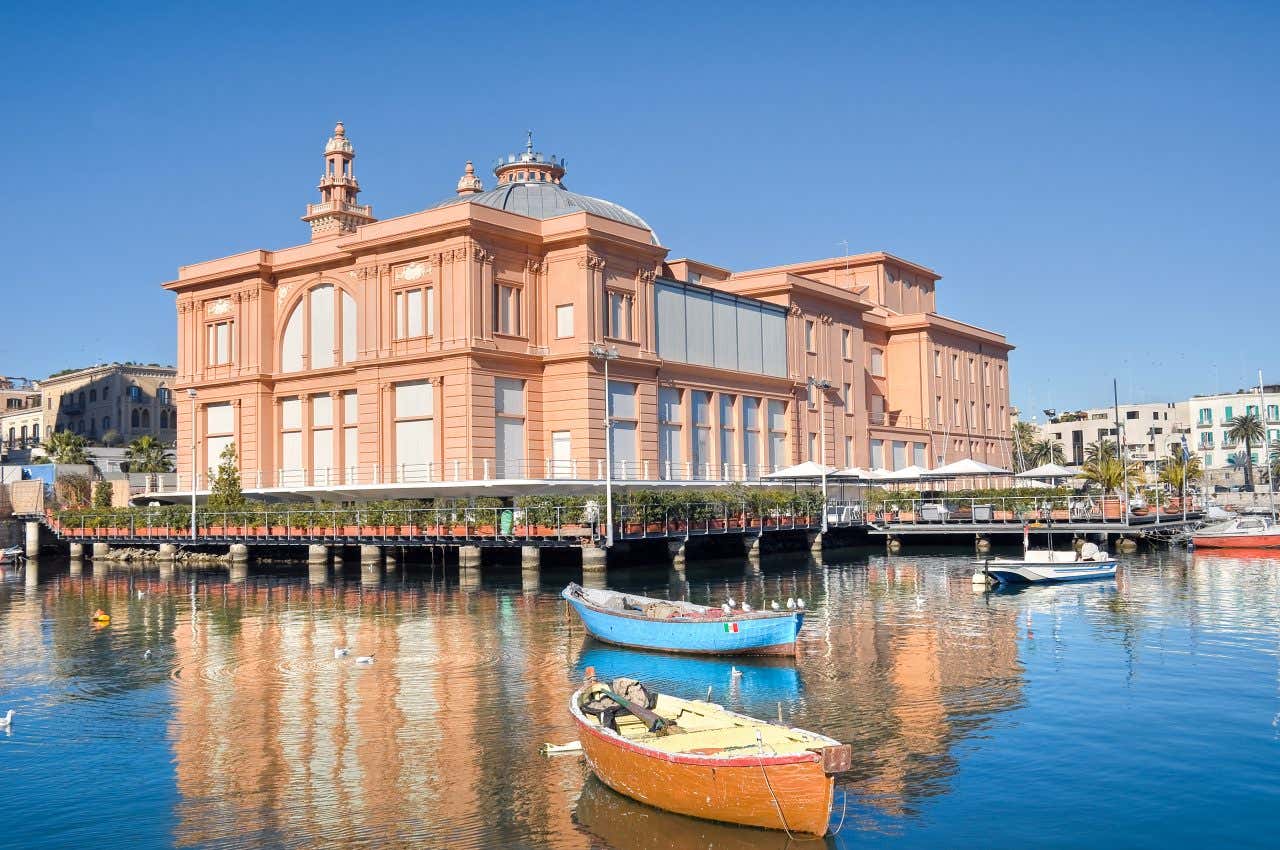 Un edificio rosa e grigio eretto su palafitte al porto vecchio di Bari