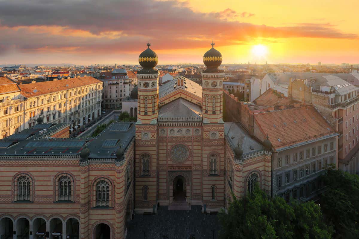 Vista aérea de la Sinagoga de Budapest al atardecer, con sus dos torres destacando por sus bulbos negros y dorados