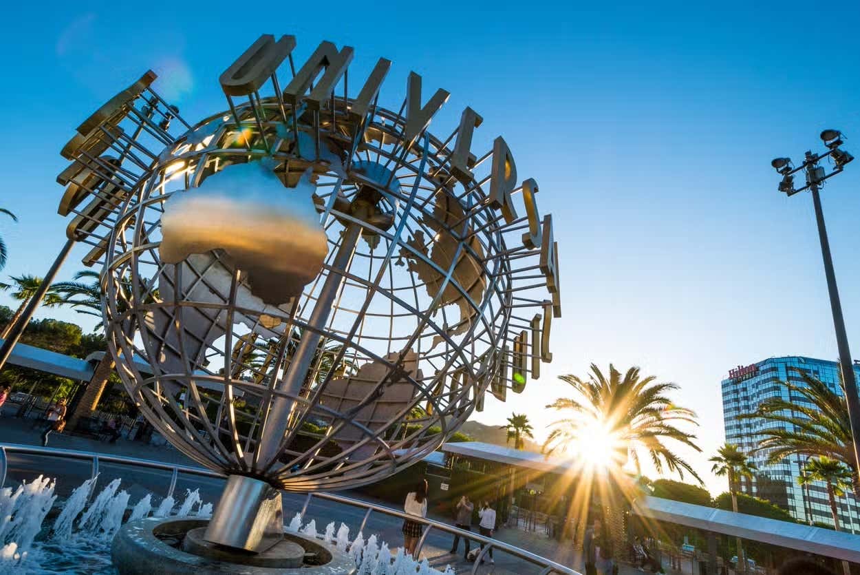 A close-up of a steel sculpture of a globe with the words 'Universal Studios Hollywood' on it