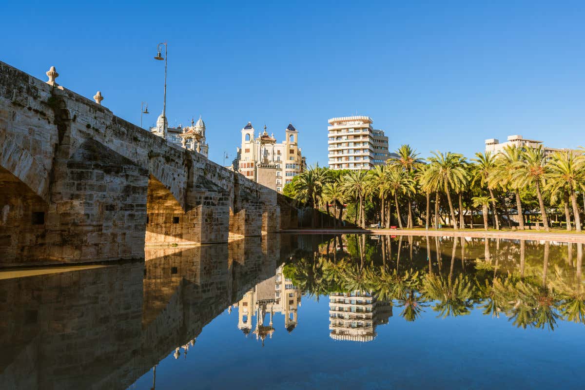 Puente del Mar, uno de los viaductos de piedra que cruzan el jardín del Turia, con vistas al río y a varias palmeras