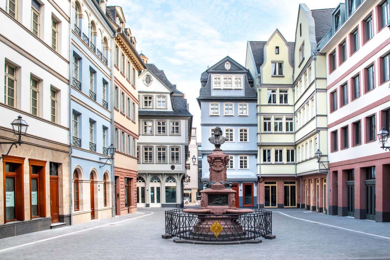 Um monumento com um busto de Friedrich Stoltze rodeada de casas coloridas