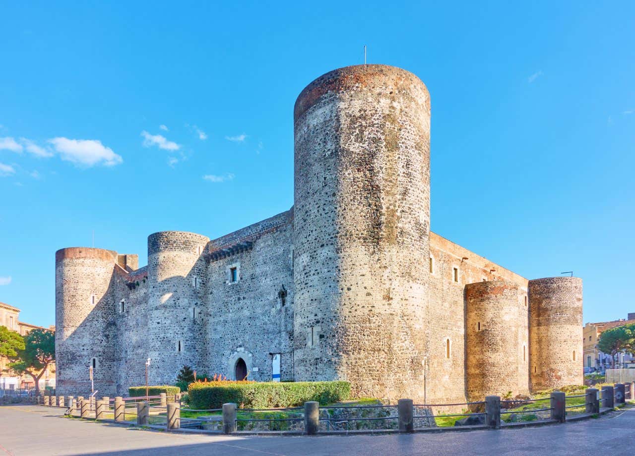 Mura esterne di un castello medievale in pietra con cinque torrioni agli angoli e ai lati del perimetro in un giorno di sole