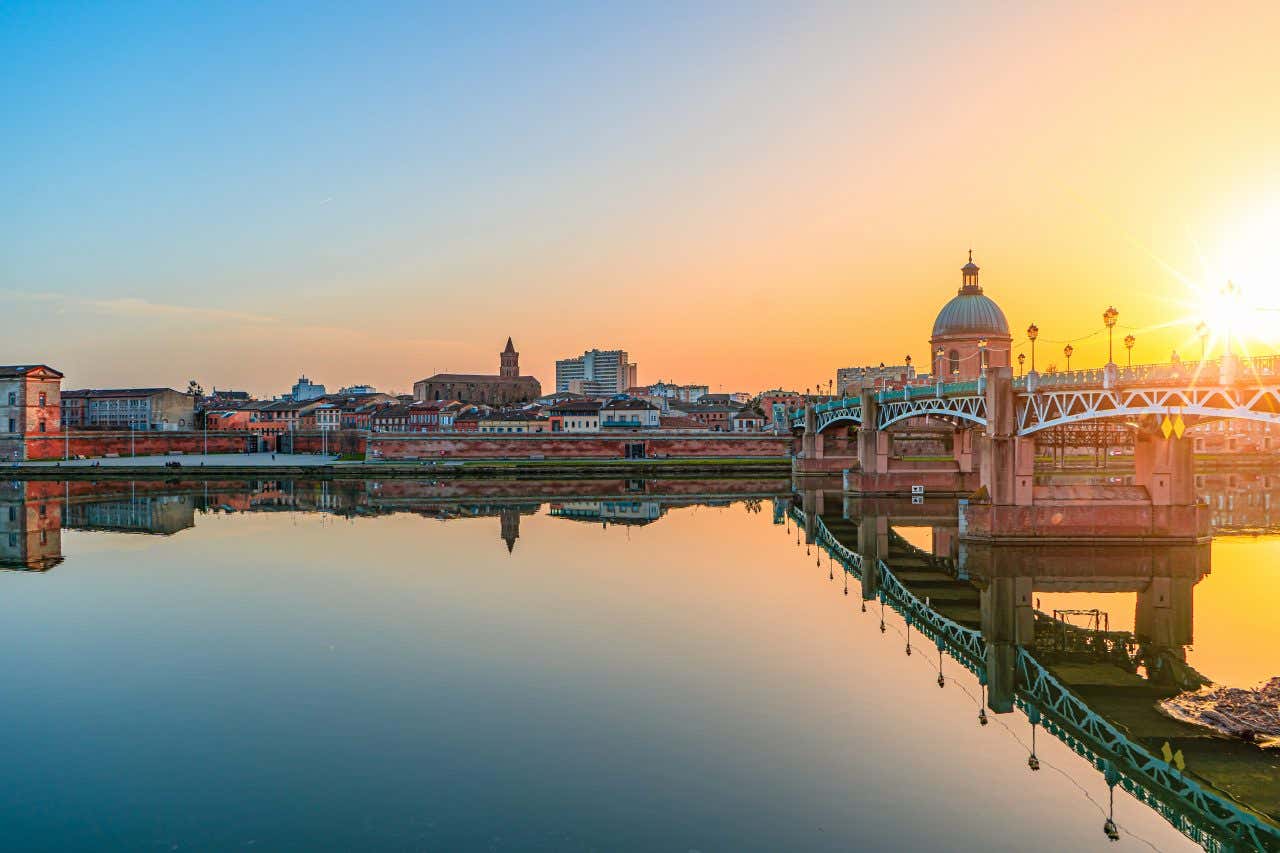 La Garonne avec un pont à droite et la ville en fond au coucher du soleil