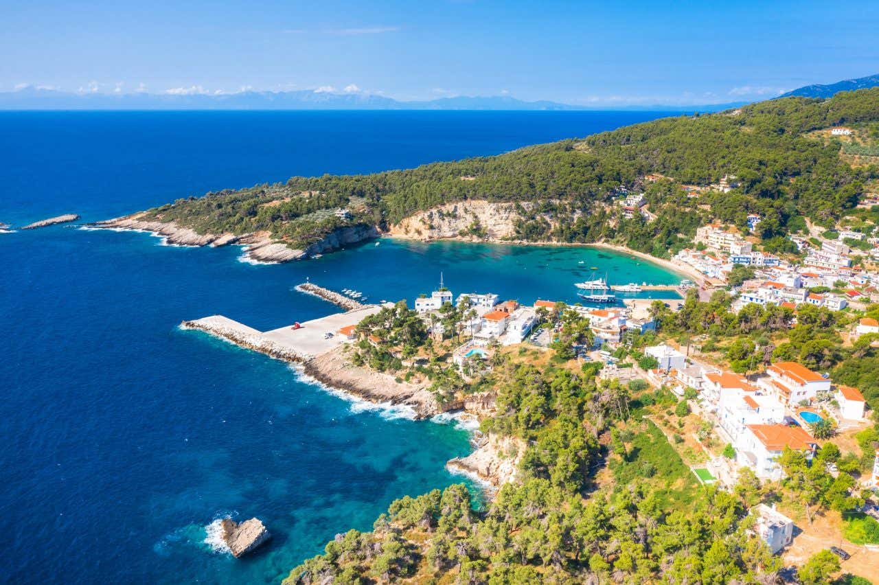 Vista aérea do porto de Patitiri, com densa vegetação, casarões e água turquesa