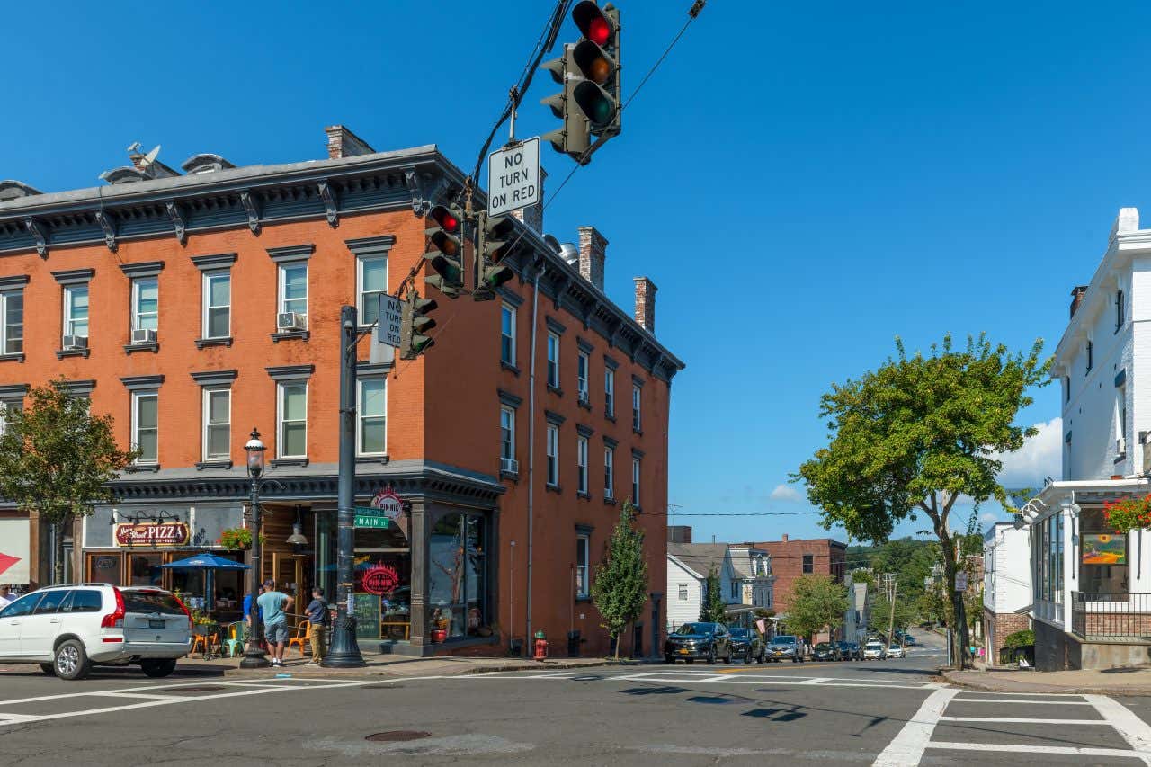 A street in Sleepy Hollow, NY, with a red brick building on the left and blue sky in the background.