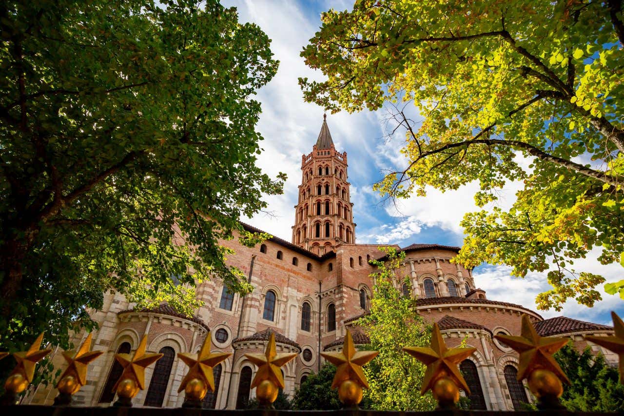 Vue en contre-plongée sur la basilique et son clocher avec des arbres au premier plan