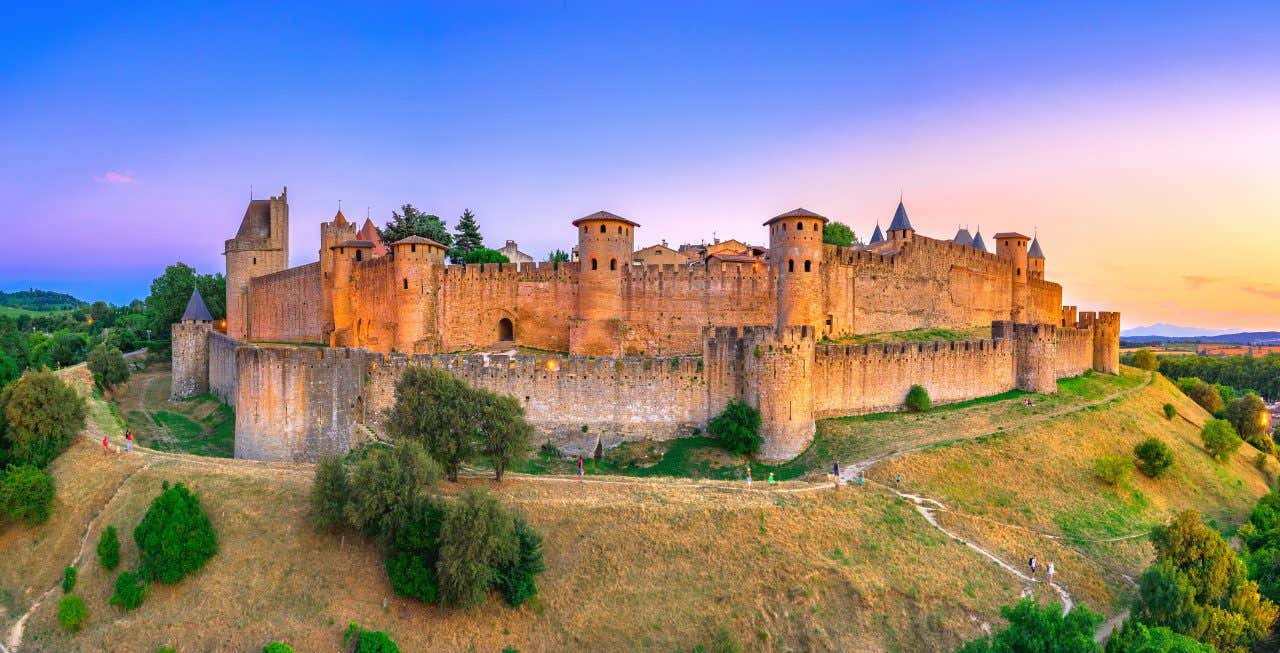 Vue sur le château de Carcassonne et ses remparts à la tombée de la nuit, un incontournable à faire près de Toulouse