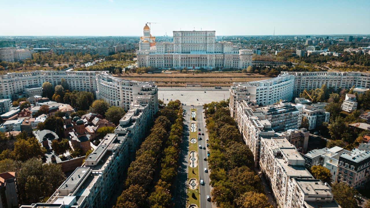 Un'imponente edificio bianco alla fine di un grosso viale in una giornata di sole